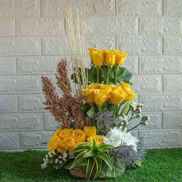 Arrangement of yellow roses , dry sticks and white chrysanthemum in a basket