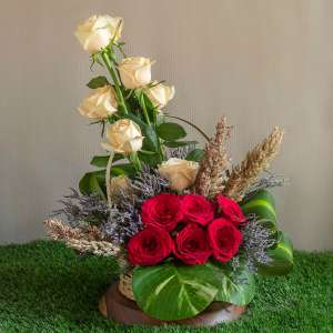 Red roses ,peach roses broom blooms and limonium in a basket